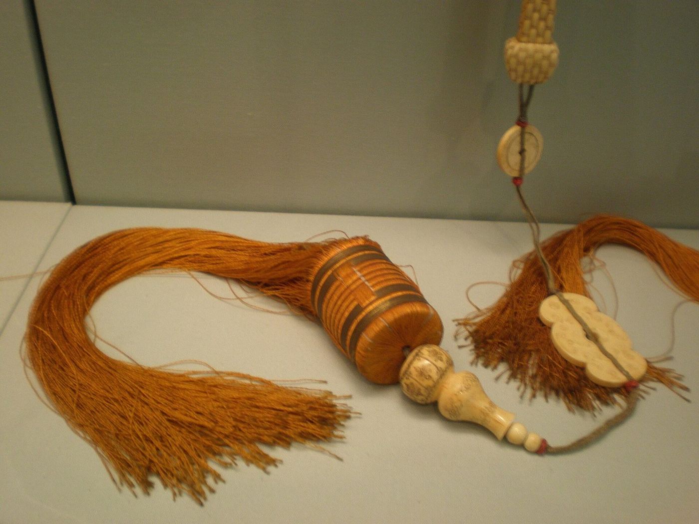 Tassels hanging from a pair of Chinese fans painted with scenes from Romance of the Western Chamber
